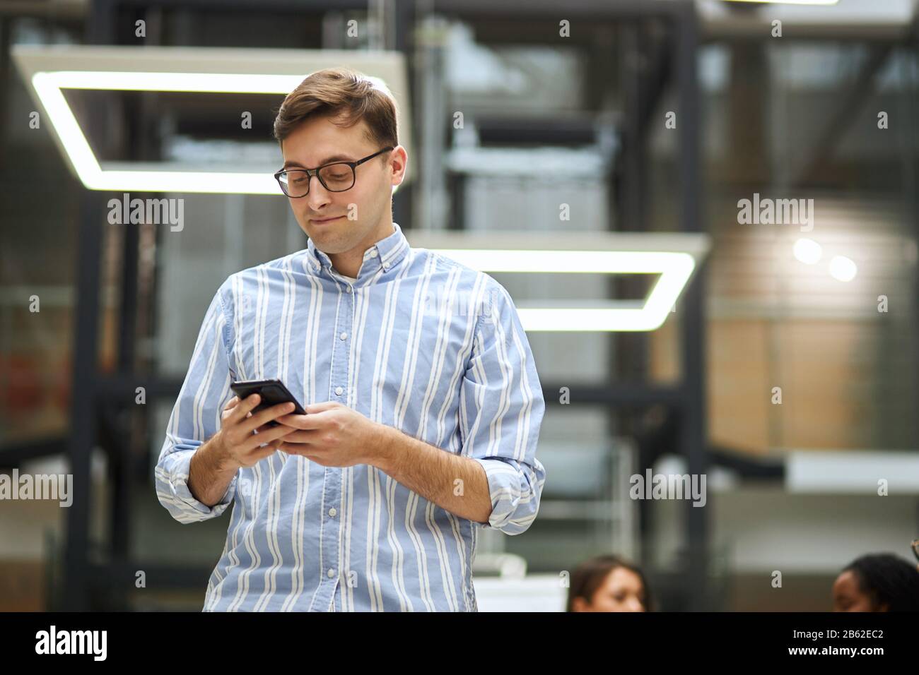 giovane uomo intelligente in occhiali che lavora con il telefono cellulare. vista a basso angolo . gadget, ragazzo brigare la rete, scaricare file, documenti, foto, musica, cercando Foto Stock