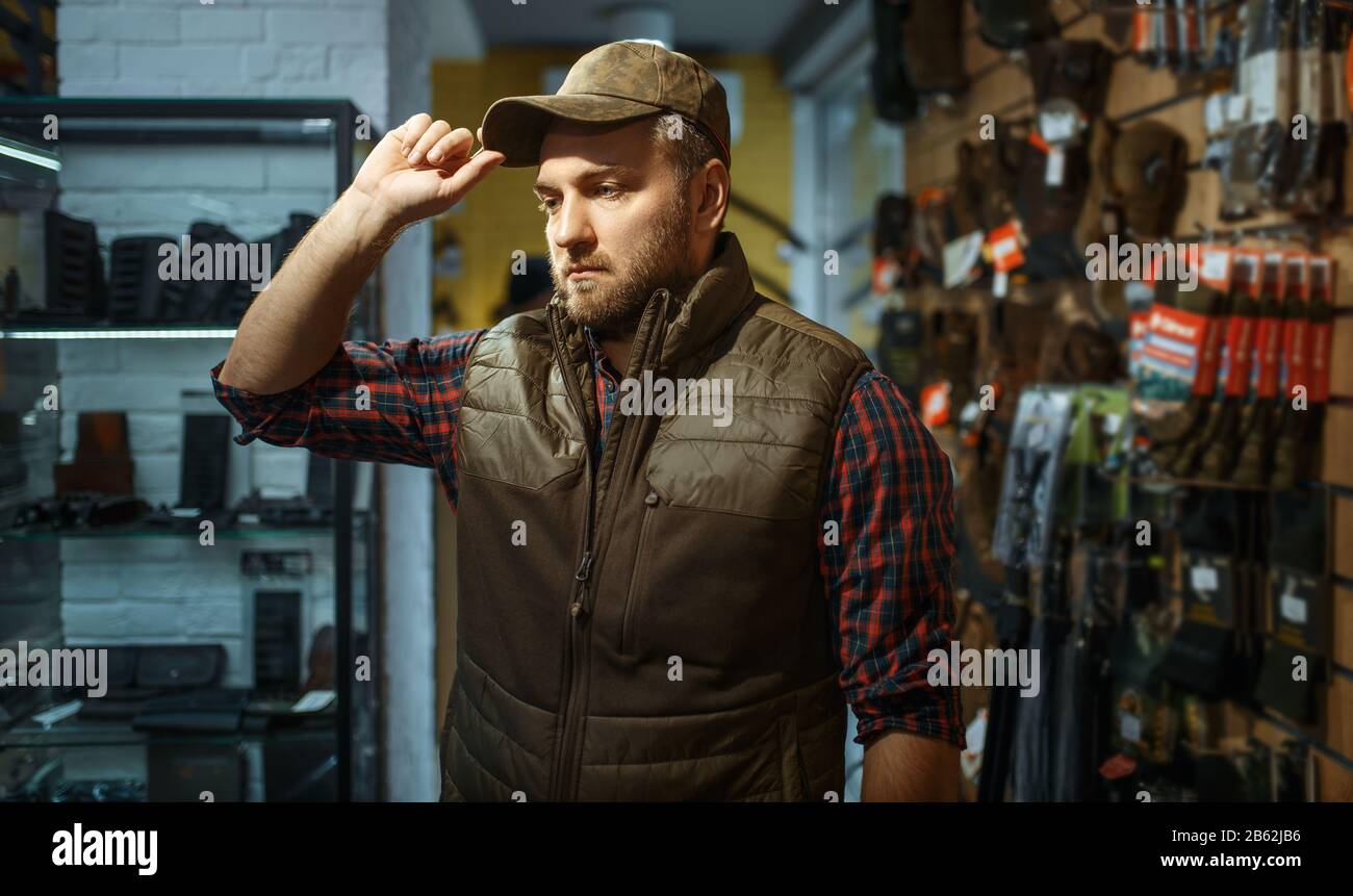 Uomo in cappellino, interno negozio di pistola sullo sfondo Foto Stock