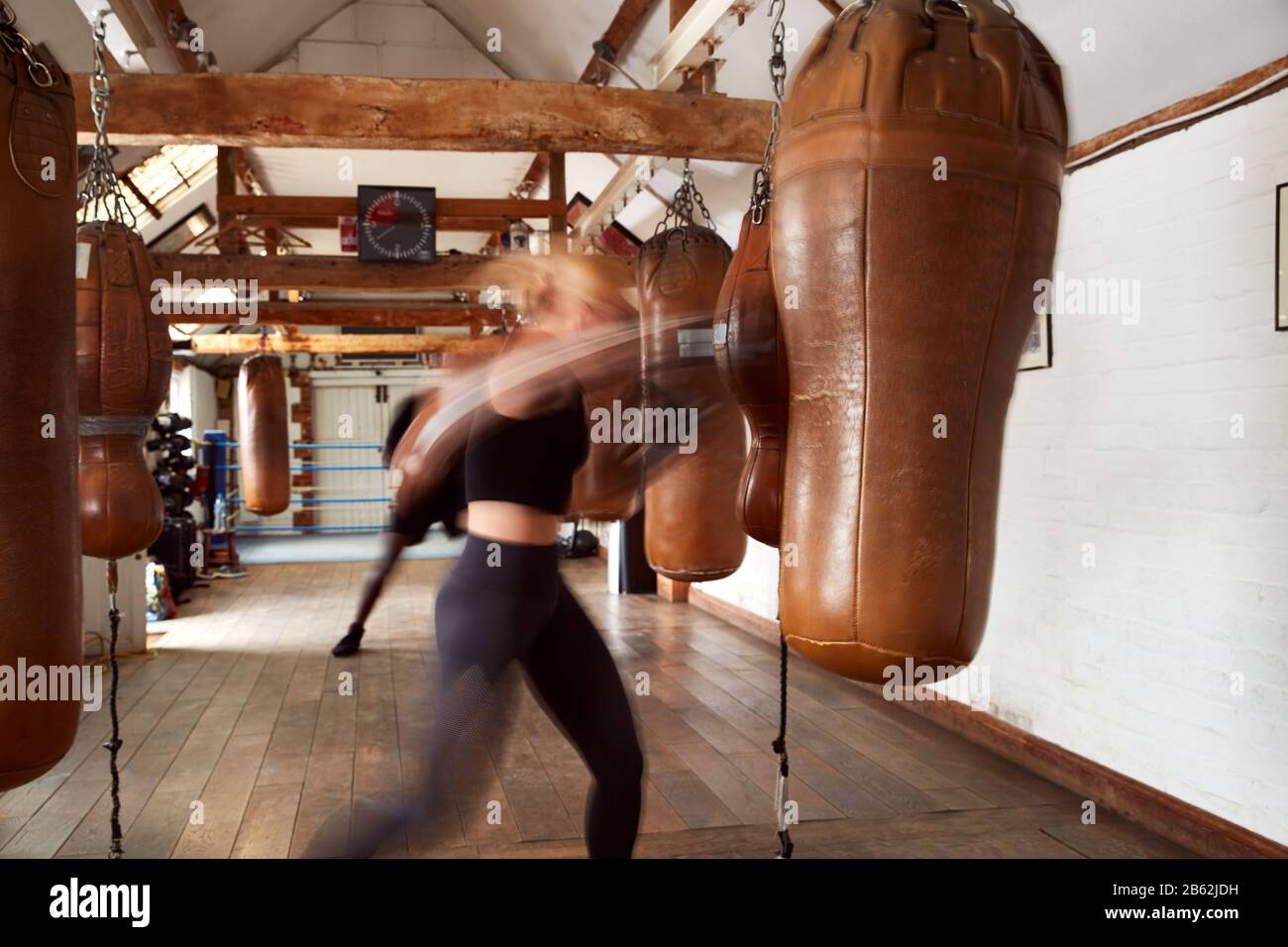 Action Shot Di Boxer Maschio E Femmina In Allenamento Palestra Con Borse In Pelle Foto Stock