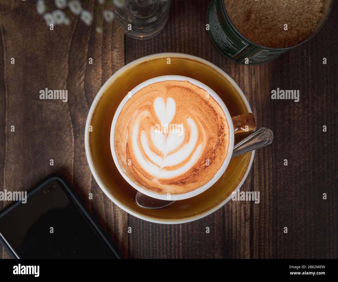 Immagine top down di un latte e cellulare che mostra la cultura del caffè o lo stile di vita del fine settimana dei Millennial Foto Stock