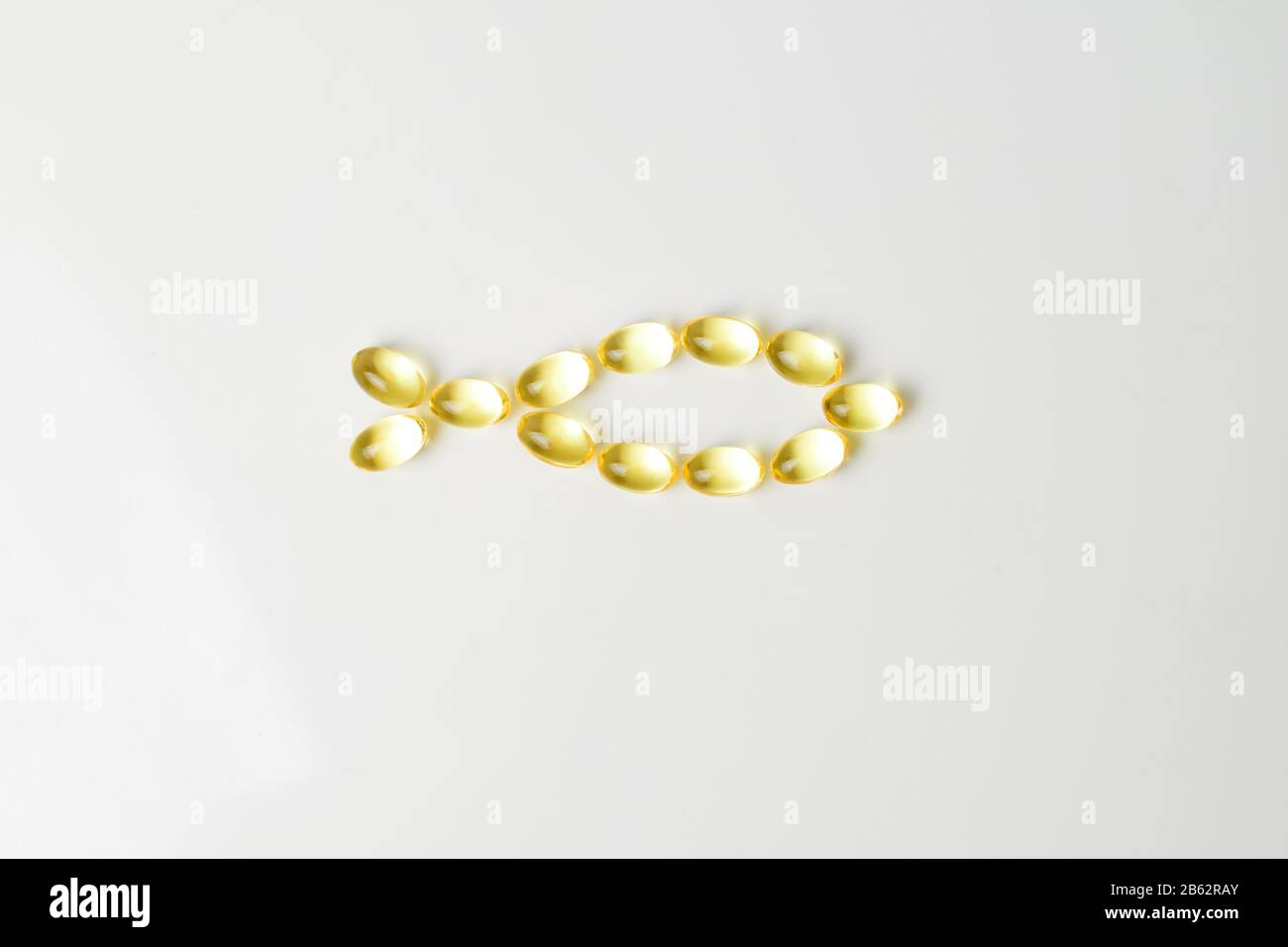 Gel di olio di pesce su sfondo bianco a forma di pesce. Sostituzione pasto. Prescrizione nutrizionale. Acidi grassi polinsaturi Omega-3. Primo piano Foto Stock