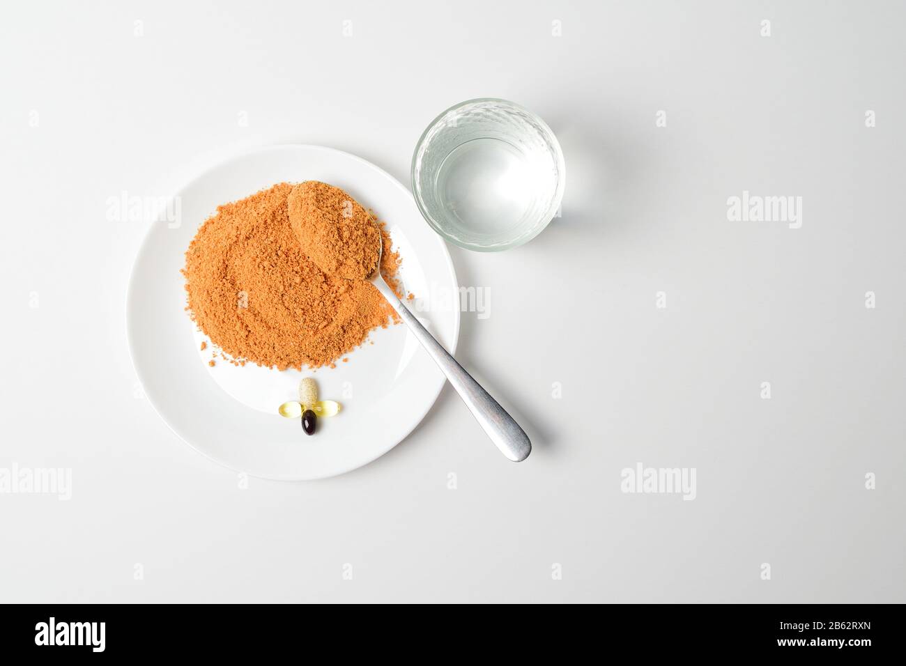 Minestra di proteine di pomodoro in polvere su un cucchiaio. Sostituzione pasto. Zuppa secca. Multivitaminici, astaxantina, olio di pesce, omega pillole su un piatto. Primo Piano. Foto Stock