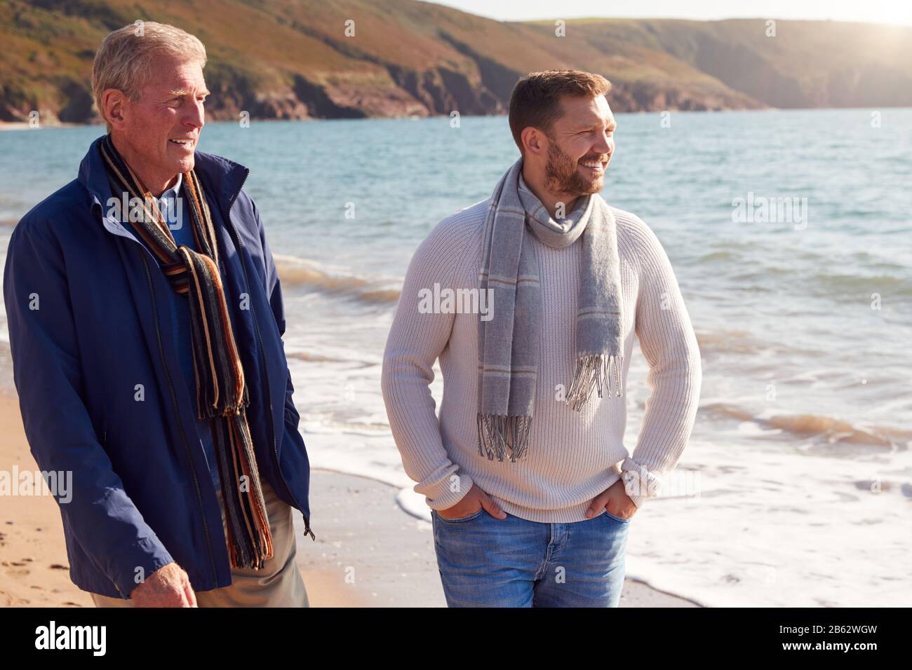 Padre Senior Con Adulto Figlio Camminare Lungo Shoreline Sulla Vacanza Invernale Spiaggia Foto Stock