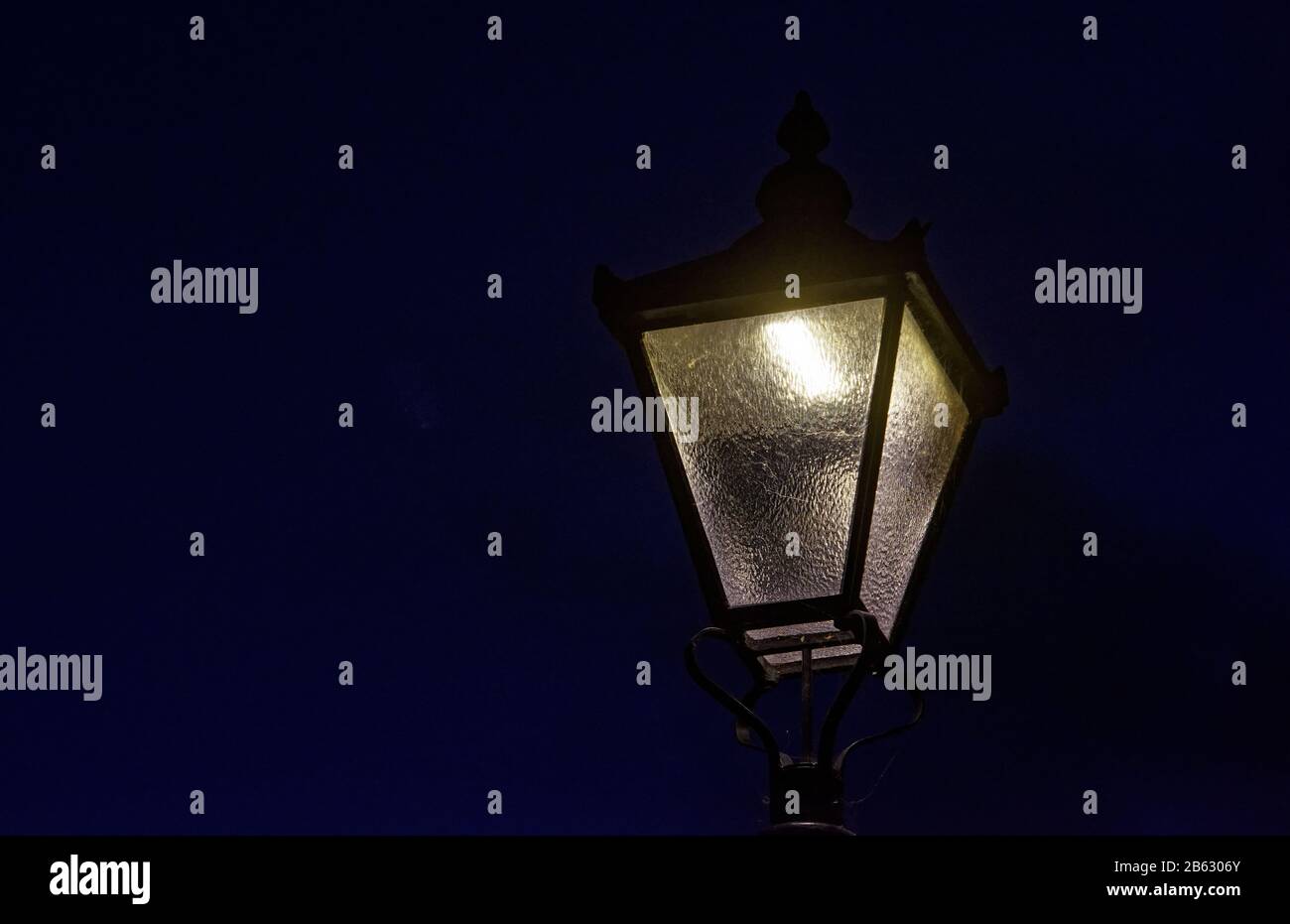 Luce di strada di stile tradizionale londinese contro un cielo nero notturno, Brentford Foto Stock