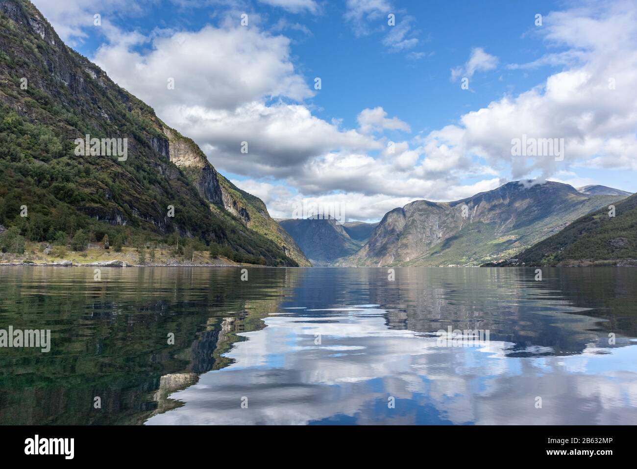 Vista dalla superficie dell'acqua con riflessione luminosa. Norvegia Aurlandsfjord viaggio, tour in kayak. Natura, montagne, paesaggio blu, vista epica nuvoloso. Foto Stock