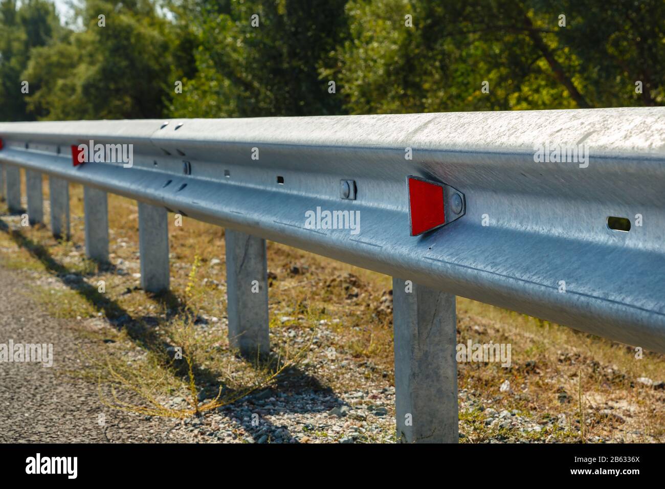 catarifrangenti stradali rossi lungo la strada. recinzioni stradali metalliche di tipo barriera. Sicurezza stradale e stradale Foto Stock