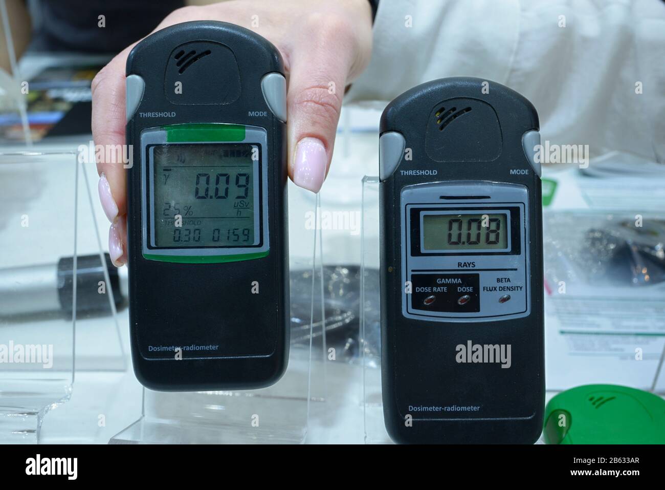 Mano del cliente che tiene i dosimetri-radiometri professionali personali per misurare i livelli di radiazione Foto Stock