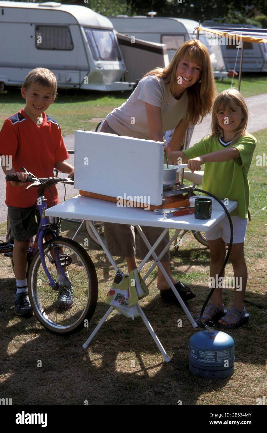 madre e due bambini che cucinano sul sito caravan Foto Stock