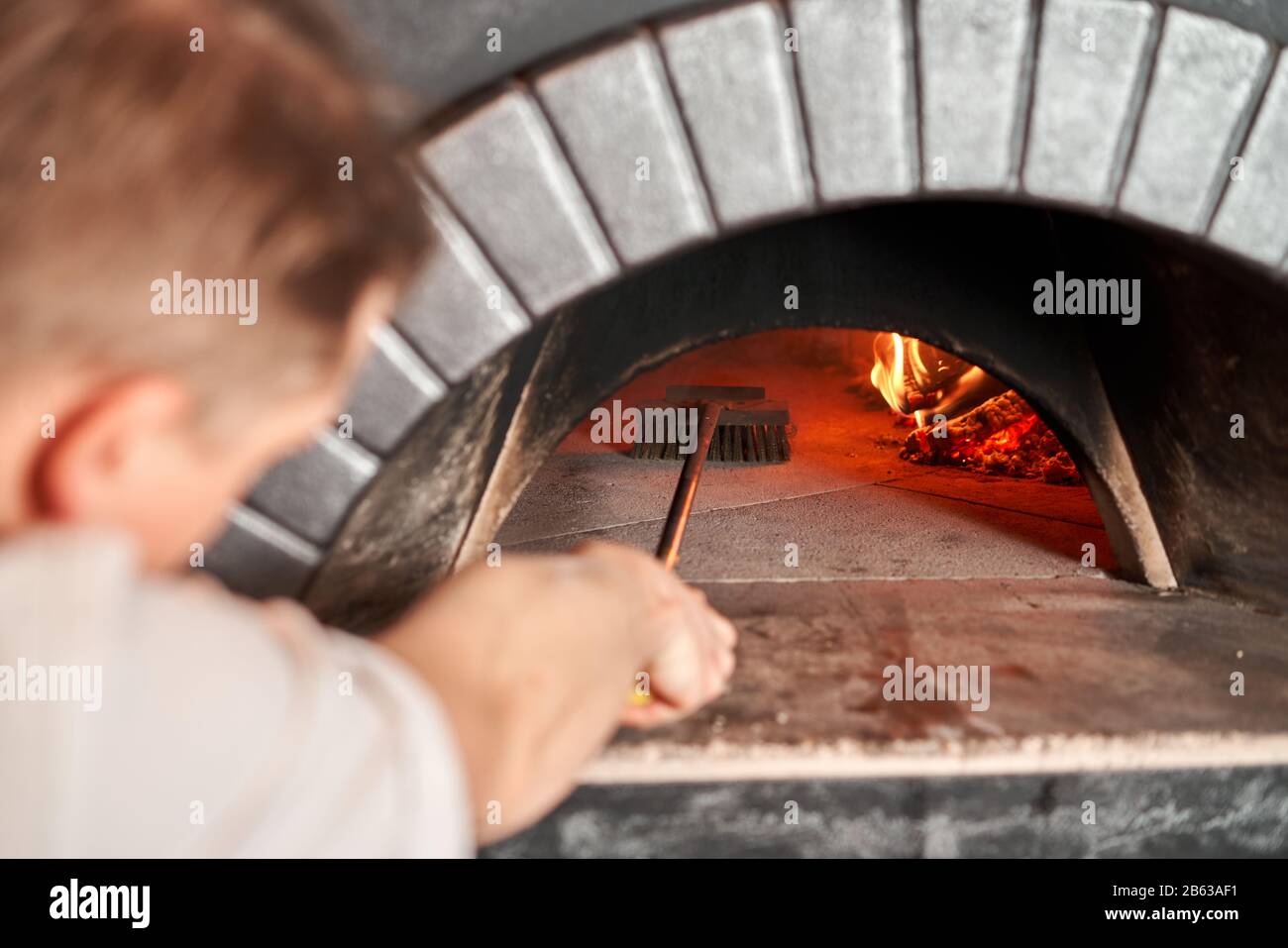 Pizza Chef pulizia forno pizza con spazzola speciale. Tradizionale forno a  legna in ristorante, Italia. Originale pizza napoletana. Carbone caldo  rosso Foto stock - Alamy
