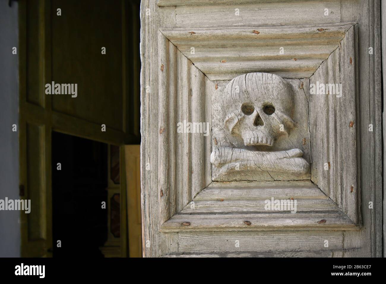 Primo piano della porta medievale in legno con teschio e ossa scolpite all'ingresso della Chiesa del Purgatorio di Matera. Foto Stock