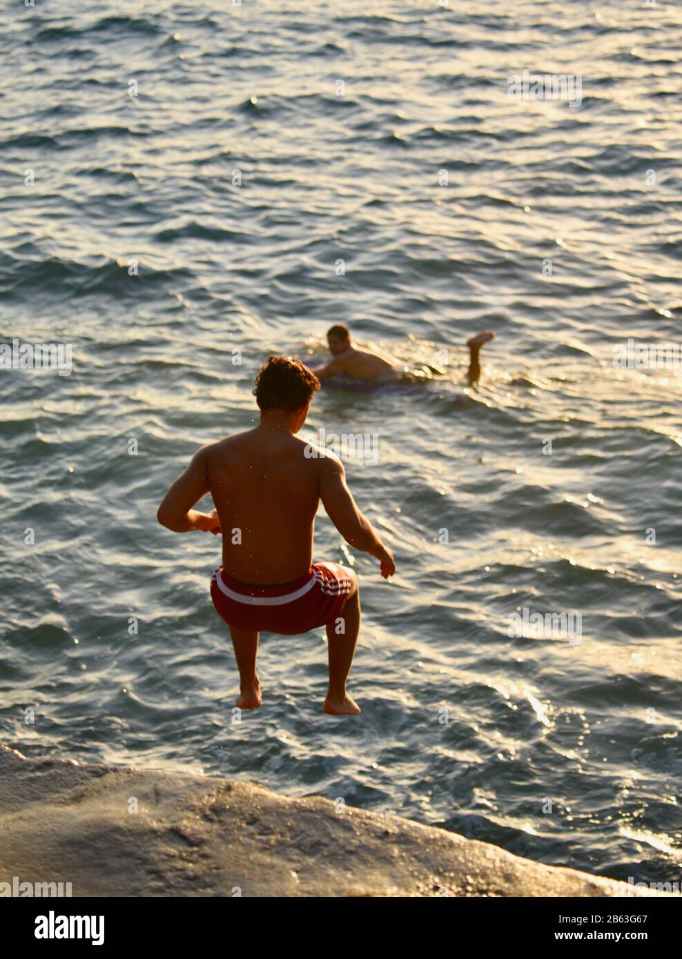 Saltatori di scogliera, indossando shorts da surf, saltando fuori dalla sporgenza nell'oceano alle Pareti della Cina sul lato est di Honolulu, isola di Oahu, Hawaii, Stati Uniti Foto Stock