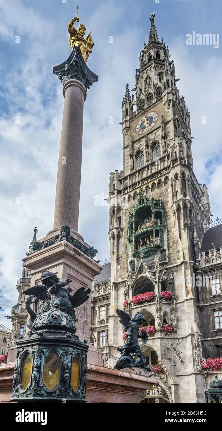 La colonna torreggiante del Mariensäule contro la facciata riccamente decorata del nuovo Municipio di Monaco (Neues Rathaus) con i suoi 85 m di altezza Rathausturm Foto Stock