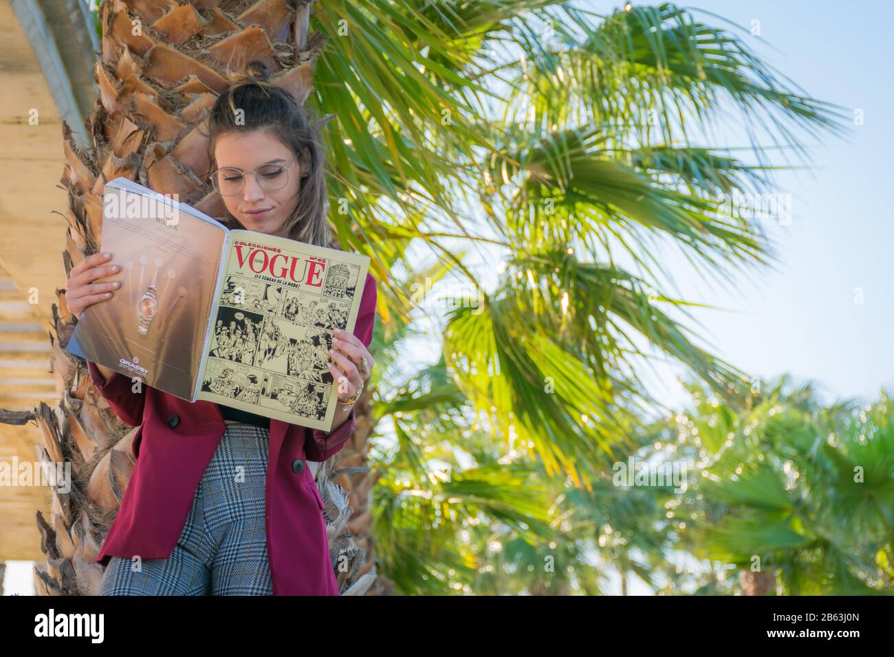 Ragazza giovane lettura Vogue in un parco Foto Stock