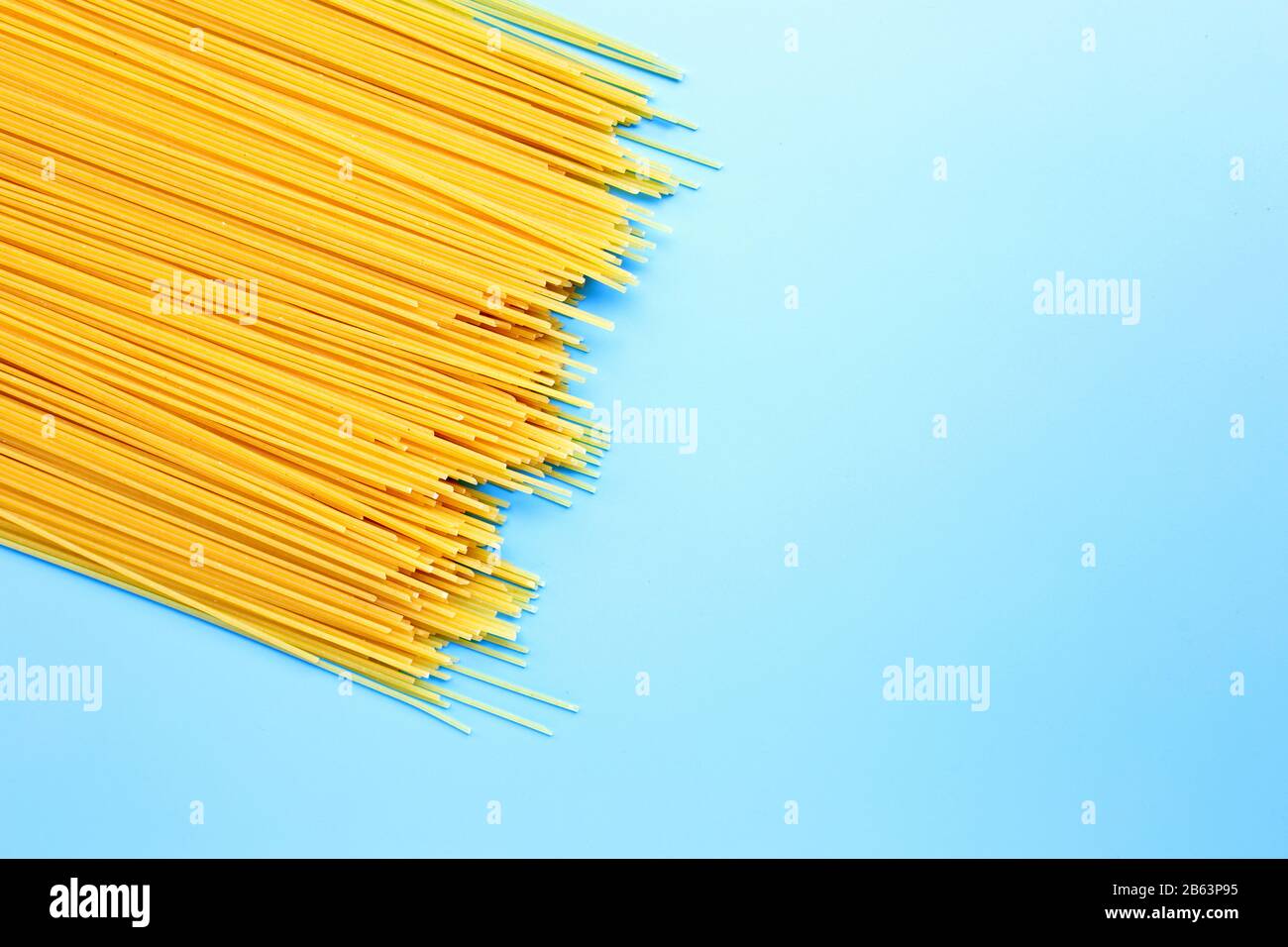 Spaghetti lunghi gialli su sfondo blu. Spazio di copia Foto Stock