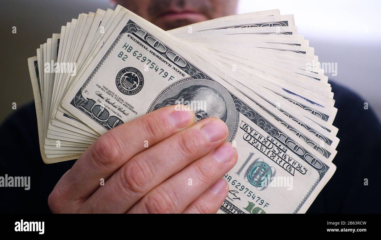 Un mucchio di banconote da 100 dollari nelle mani di un uomo Foto Stock