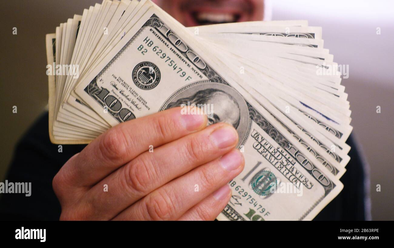 Un mucchio di banconote da 100 dollari nelle mani di un uomo Foto Stock