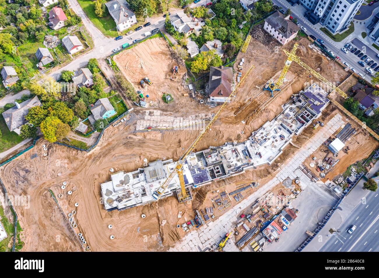 vista aerea dall'alto del sito di costruzione della città con gru a torre gialle funzionanti e macchine da costruzione Foto Stock
