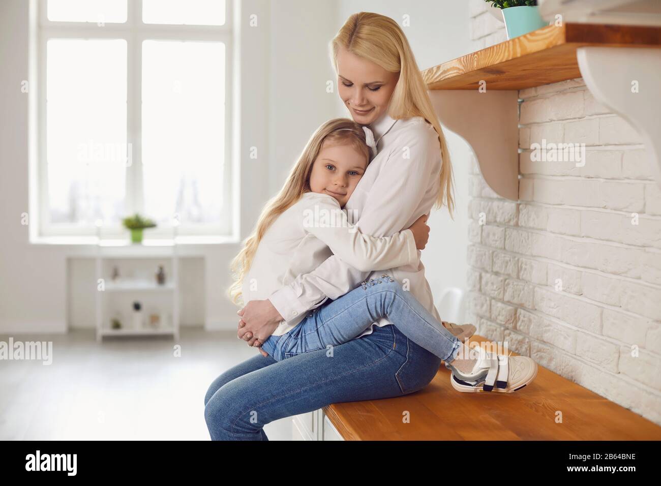 Buon giorno della madre. Madre e figlia che abbracciano sorridendo a casa. Foto Stock