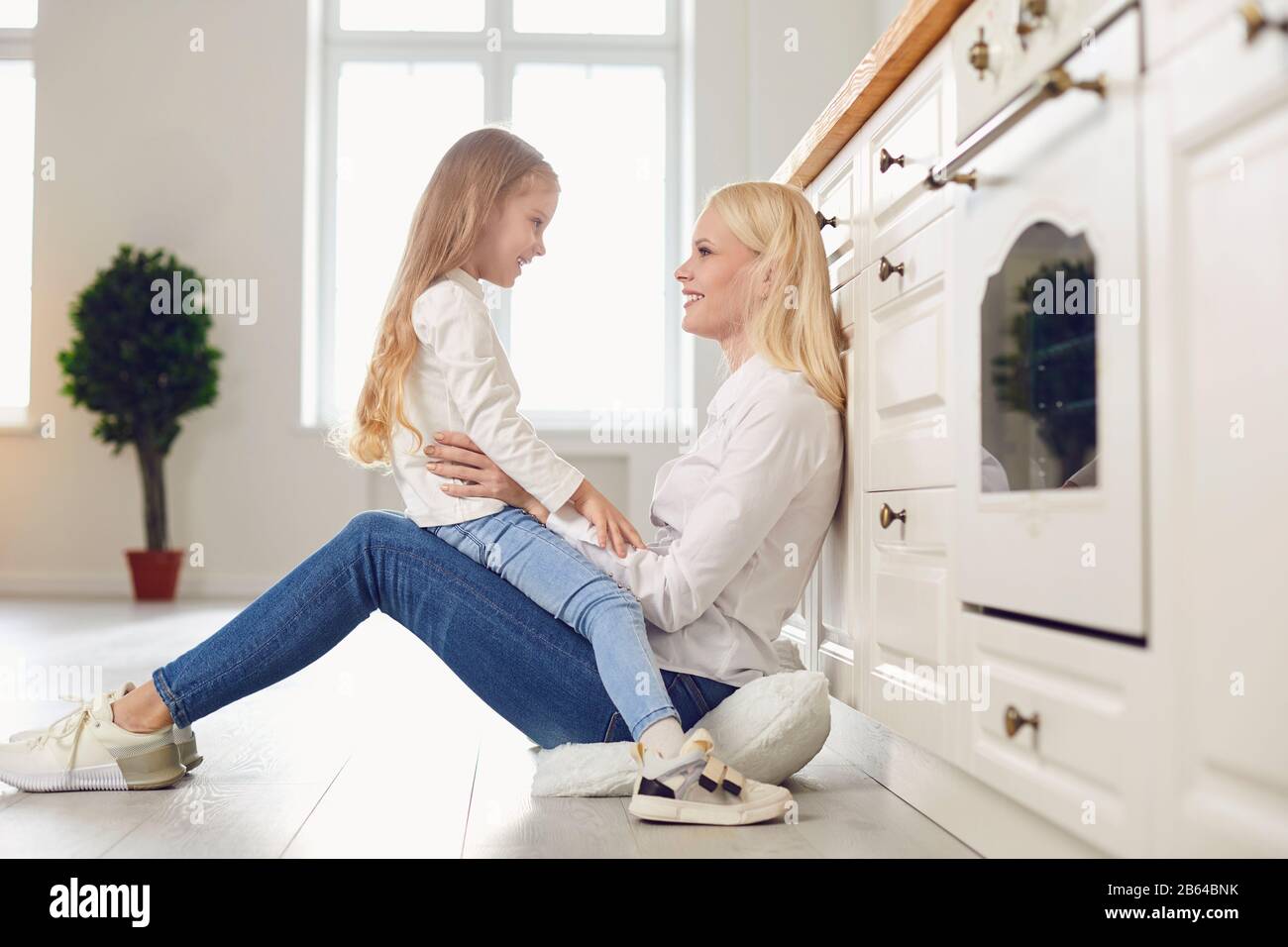 Buon giorno della madre. Madre e figlia che abbracciano sorridendo in cucina. Foto Stock