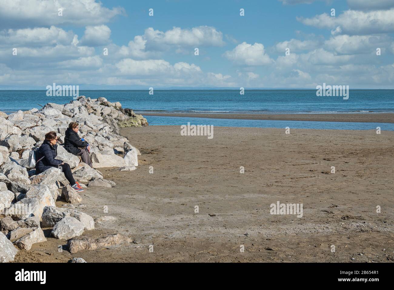 due donne seduti sulle pietre sulla spiaggia nella stagione invernale Foto Stock