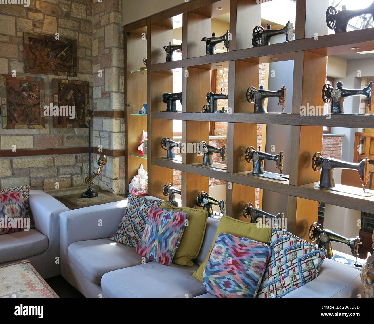Vista parziale del soggiorno decorato con una collezione di macchine da cucire vintage su una libreria e divani colorati con cuscini. Foto Stock