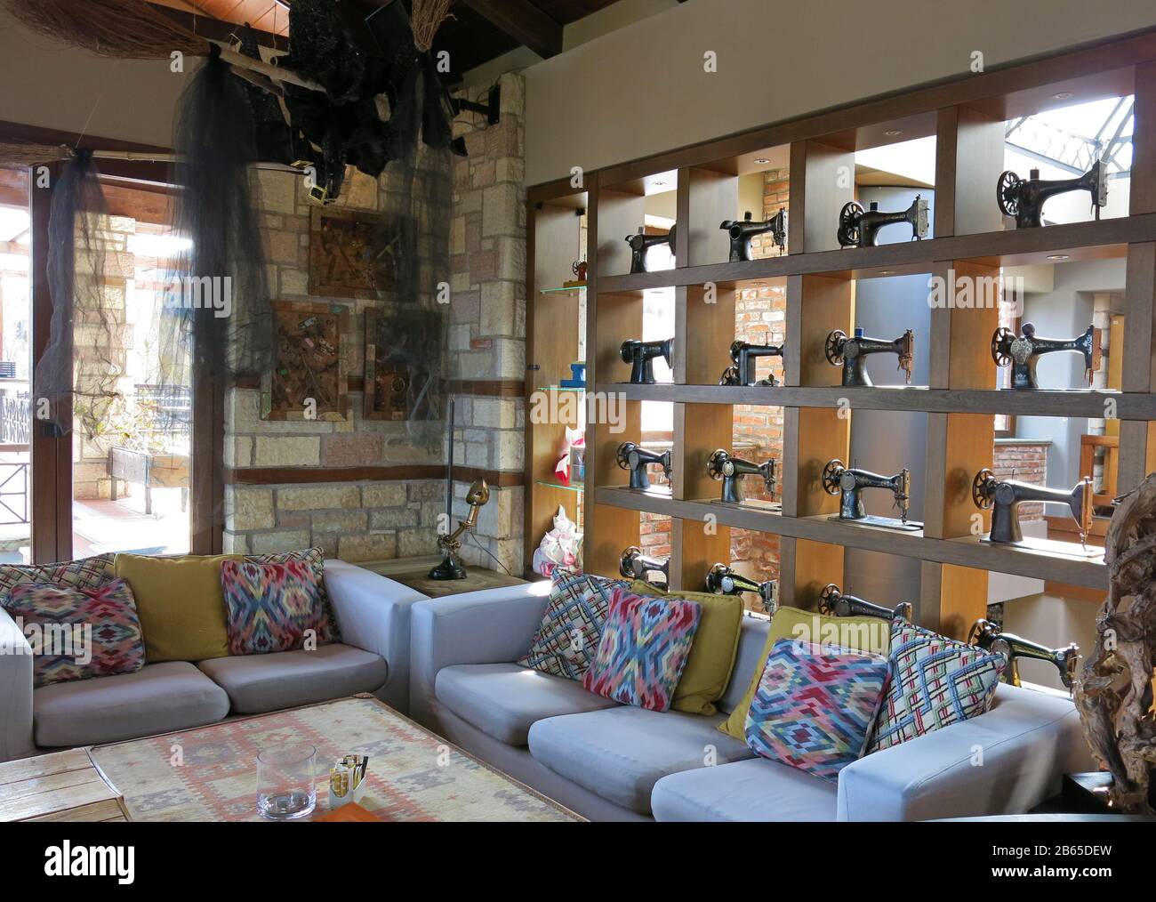 Vista parziale del soggiorno decorato con una collezione di macchine da cucire vintage su una libreria e divani colorati con cuscini. Foto Stock