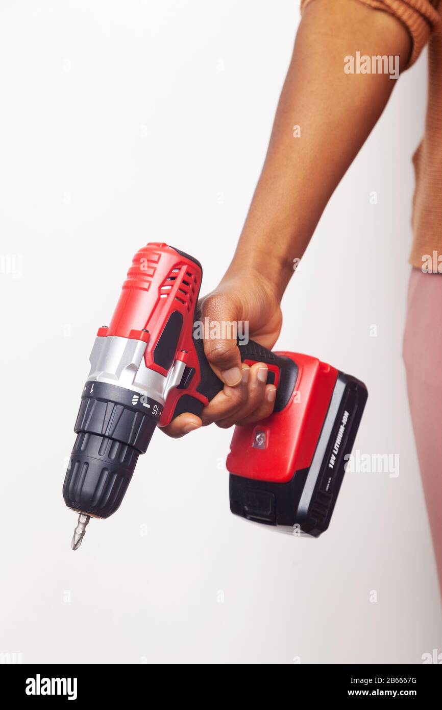 La mano di una donna di etnia africana che tiene in mano un cacciavite a batteria Foto Stock