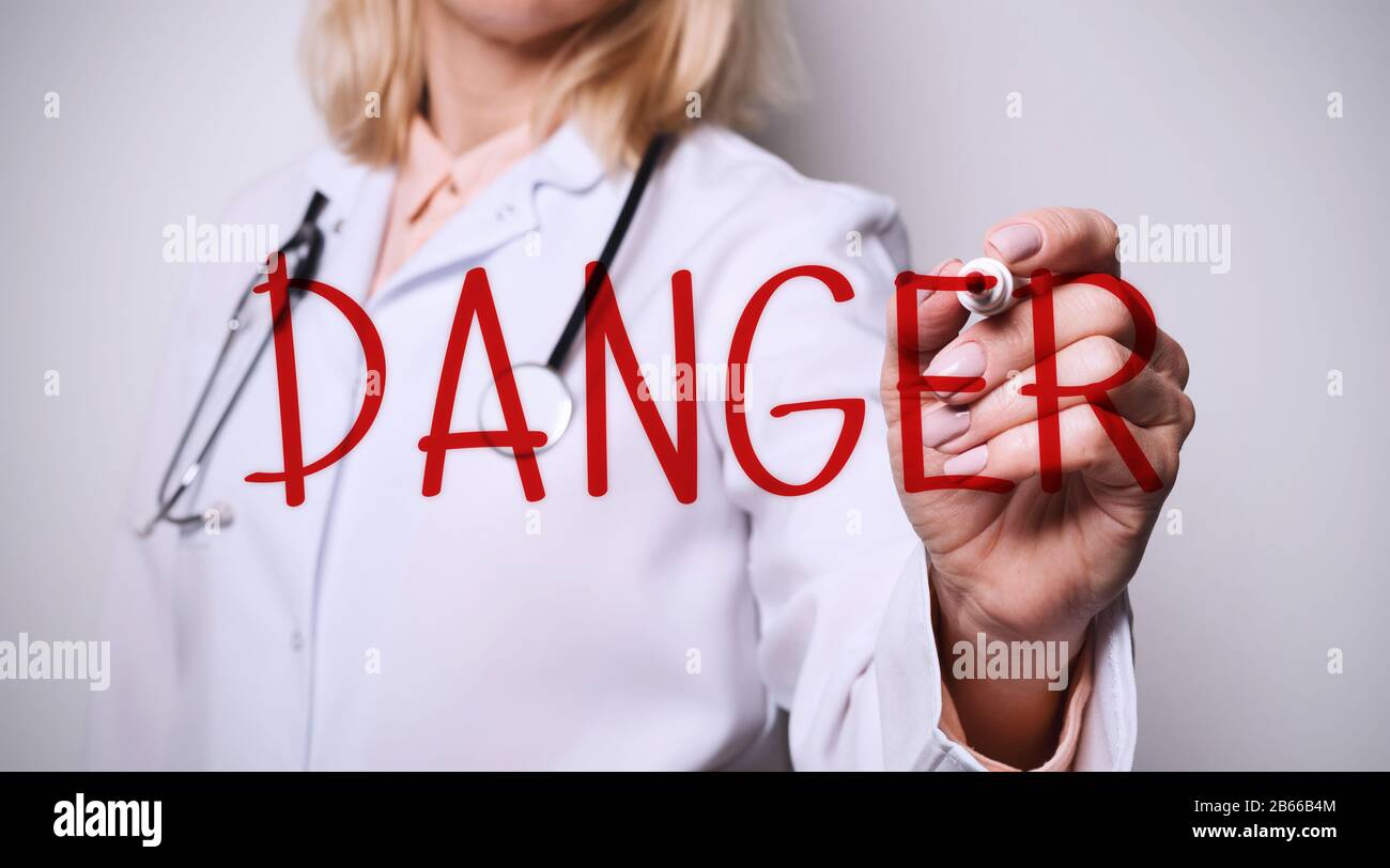 Parola di scrittura medic femminile PERICOLO sullo schermo immaginario contro sfondo bianco, closeup Foto Stock