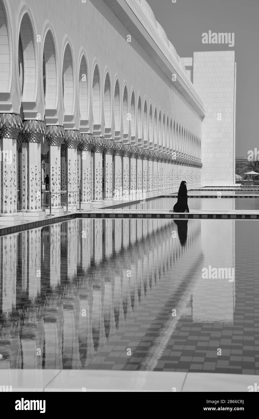 Riflesso di una signora che attraversa il bassin della moschea di Scheikh Zayed Foto Stock