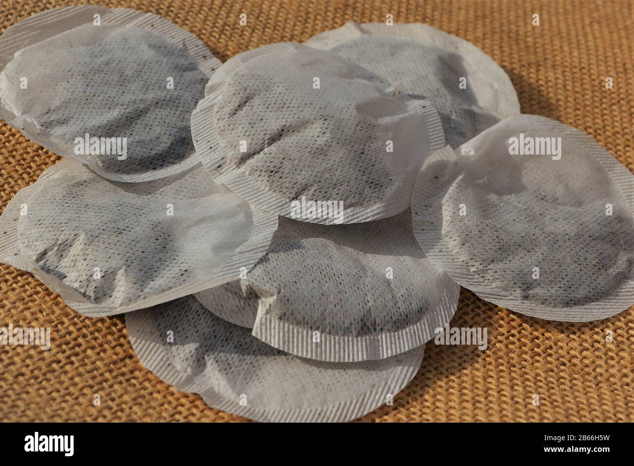 Primo piano di bustine di tè rotonde forate su fondo di sacco di hessian Foto Stock