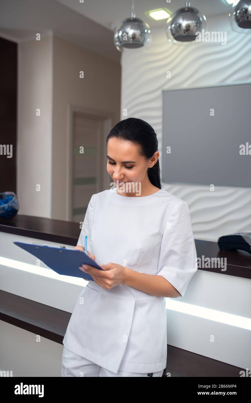 Receptionist della clinica di bellezza che fa note degli appuntamenti Foto Stock