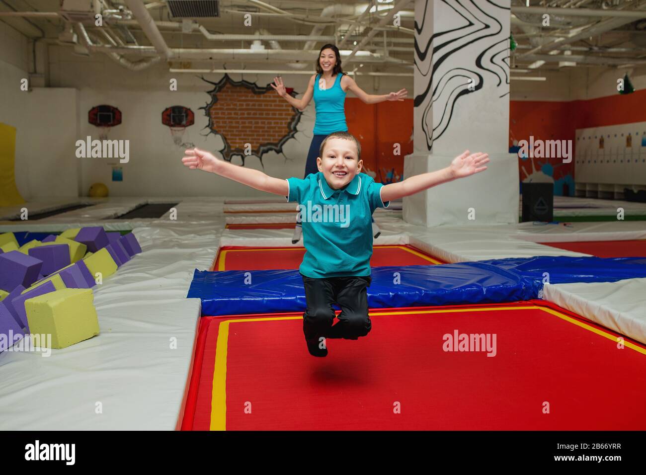 buona famiglia su un trampolino di madre e un bambino ragazzo sta saltando e giocando su un trampolino nel centro sportivo Foto Stock