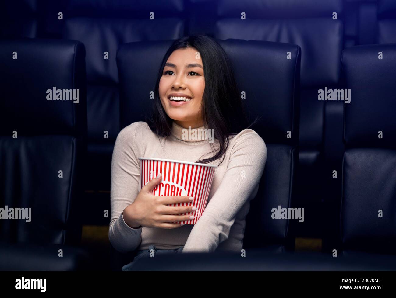 Andare a film da solo concetto. Bella donna asiatica con popcorn godendo film nel cinema Foto Stock