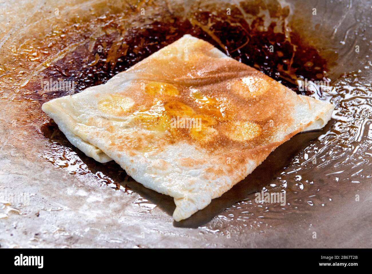Cucinare il tradizionale thailandesi roti gulay (banana pancake) in una padella Foto Stock