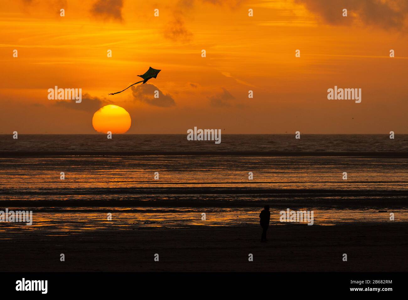 Un aquilone solitario con coda si staglia sopra il sole che tramonta mentre affonda nel mare irlandese a Lytham st annes Foto Stock
