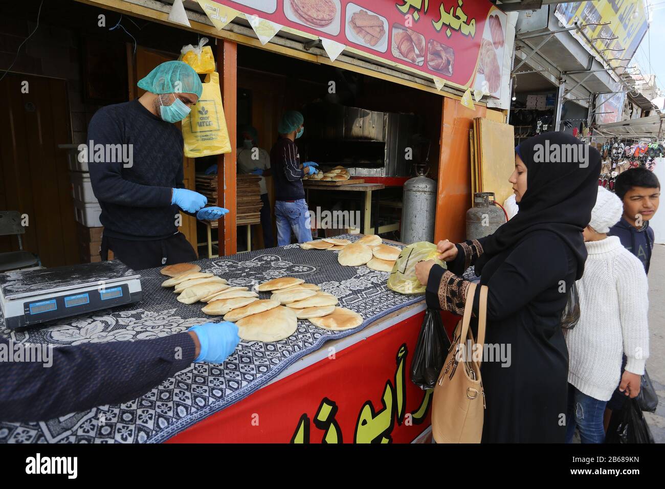 I lavoratori palestinesi che indossano maschere in mezzo alle precauzioni del coronavirus, cuocono il pane in una panetteria, a Rafah nella striscia meridionale di Gaza, il 10 marzo 2020. Foto Stock