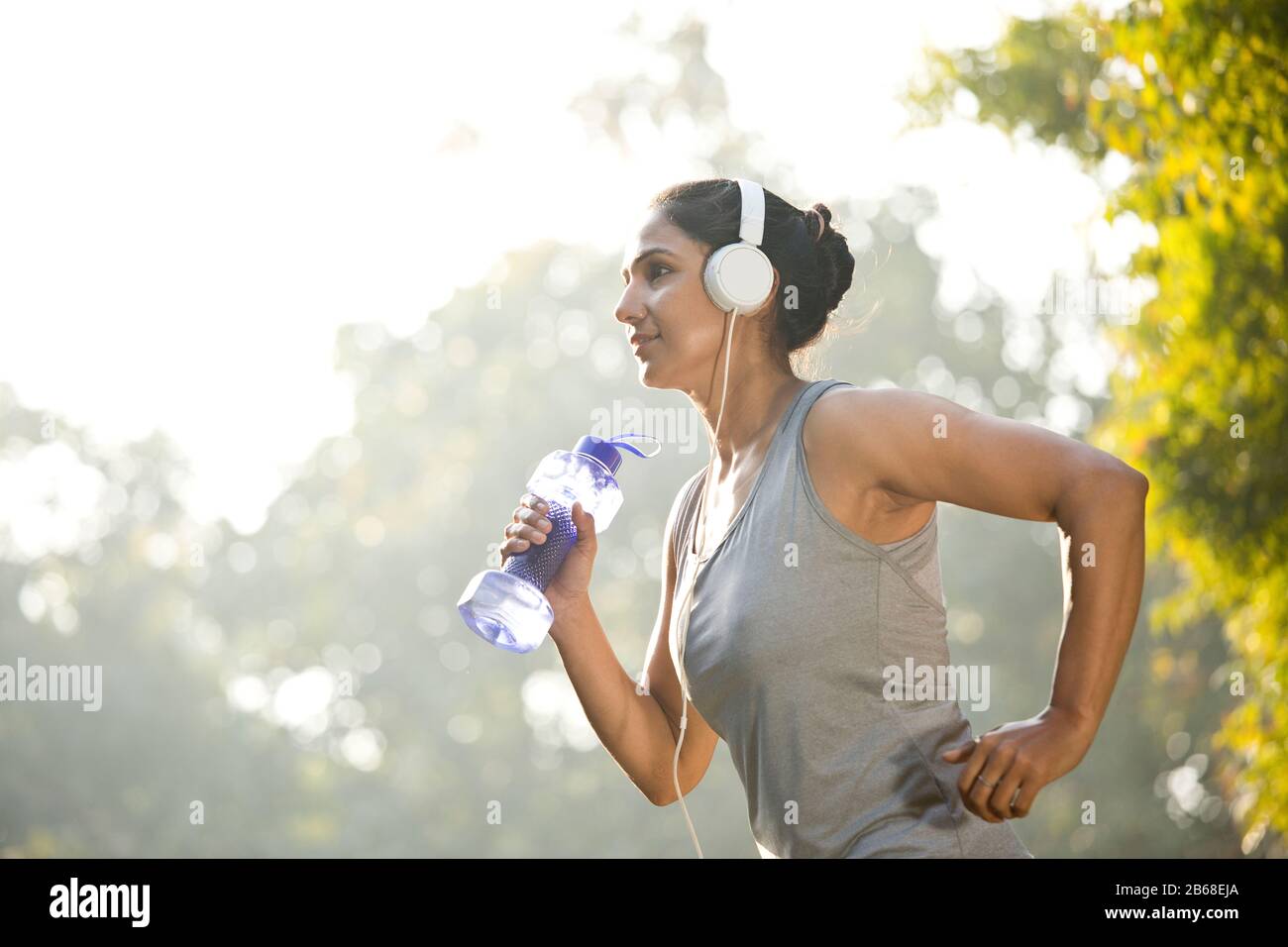 Donna in musica d'ascolto abbigliamento sportivo mentre si allenano al parco all'aperto Foto Stock