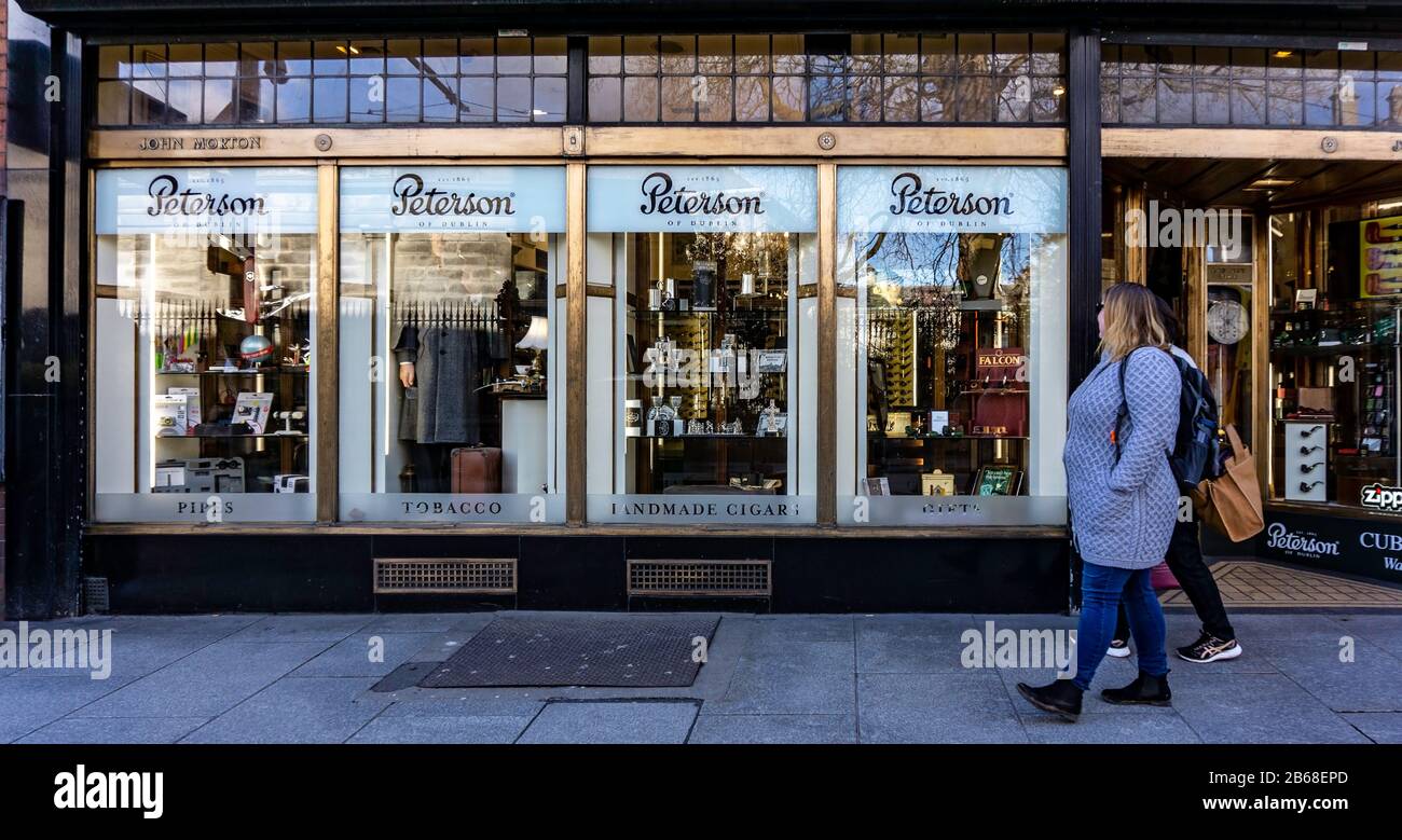 Gli amanti dello shopping passano davanti al negozio di sigari e tabacchi Peterson a Nassau Street, Dublino, Irlanda. Una volta commerciato come gioielliere John Morton. Foto Stock