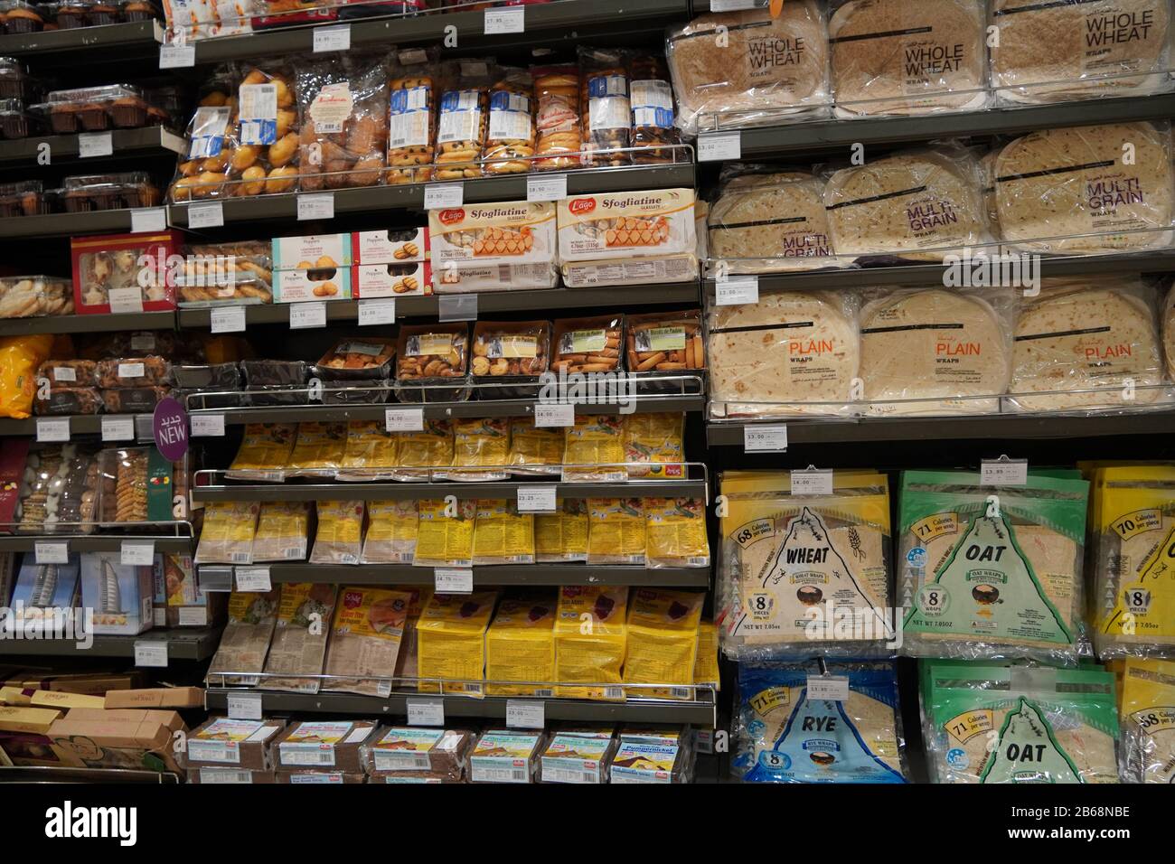 Pane fresco diverso sugli scaffali in panetteria. Interno di un negozio di alimentari moderno che mostra la navata del pane con una varietà di pane preconfezionato ava Foto Stock