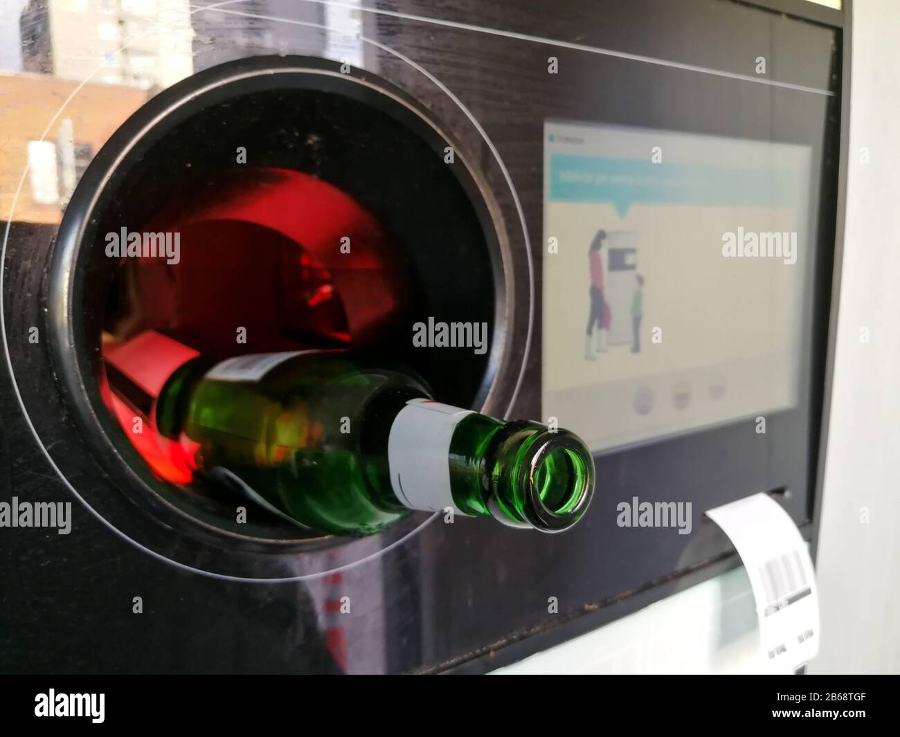 Chiusura della bottiglia di birra in vetro verde inserita nel distributore automatico inverso per il riciclaggio Foto Stock