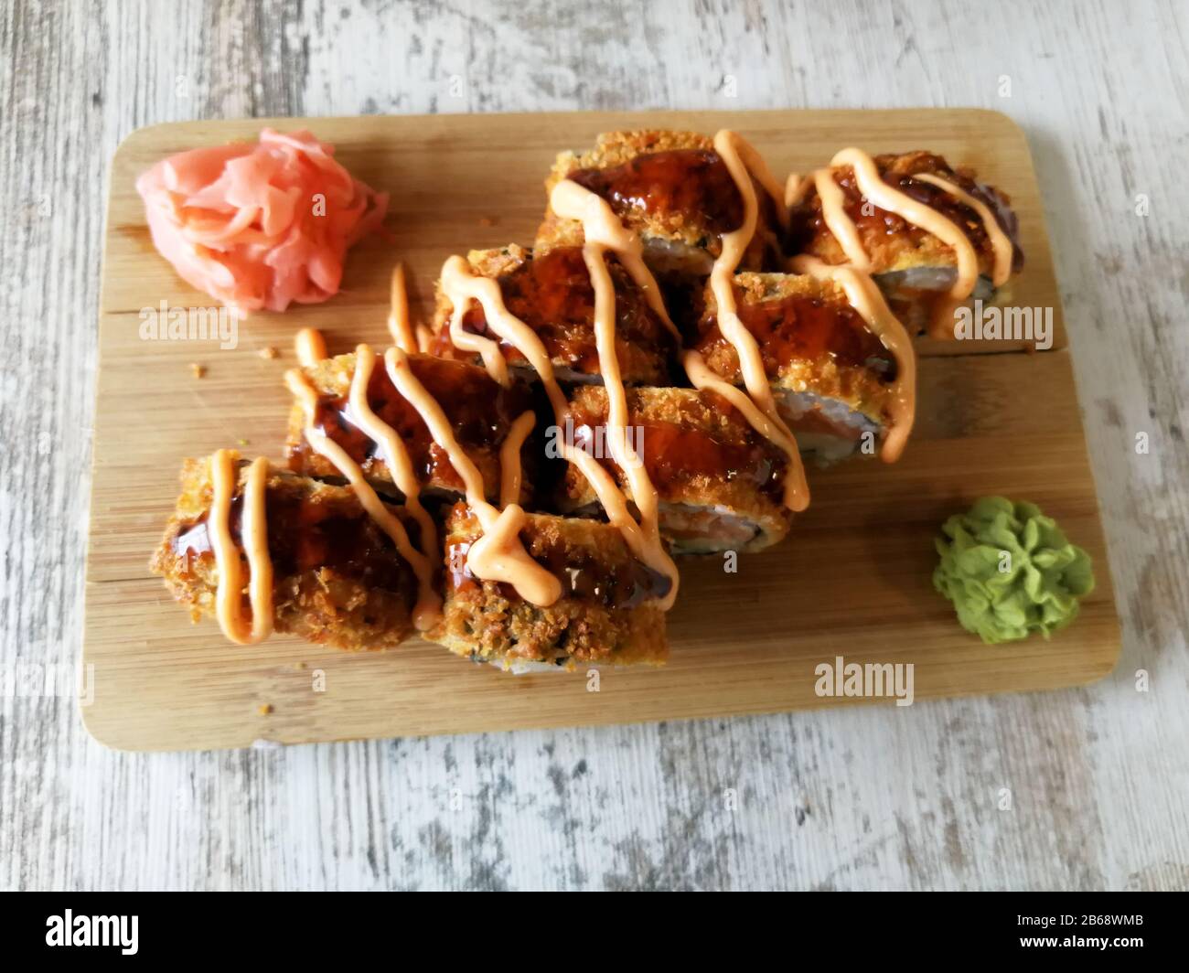 Involtini di sushi fritti caldi con salmone, formaggio e avocado con zenzero e wasabi Foto Stock