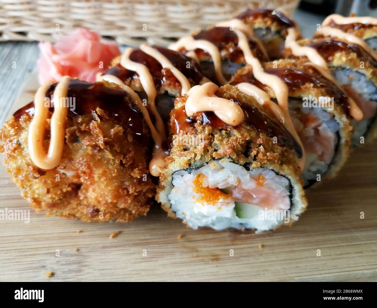 Involtini di sushi fritti caldi con salmone, formaggio e avocado con zenzero e wasabi Foto Stock