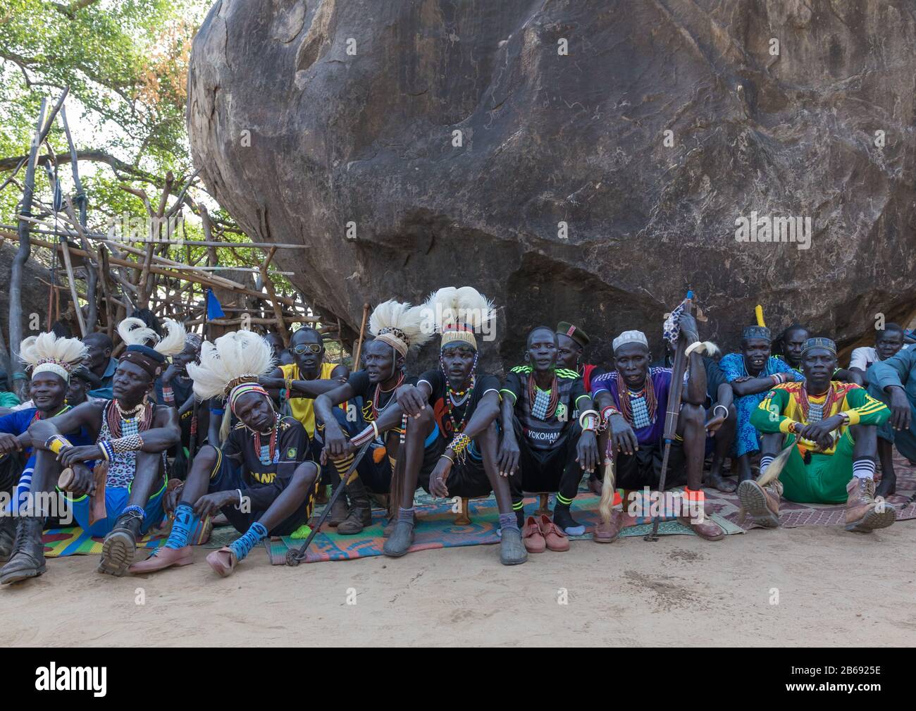 Gli uomini della tribù Lariim sotto una roccia gigante durante una celebrazione di nozze, montagne di Boya, Imatong, Sudan del sud Foto Stock
