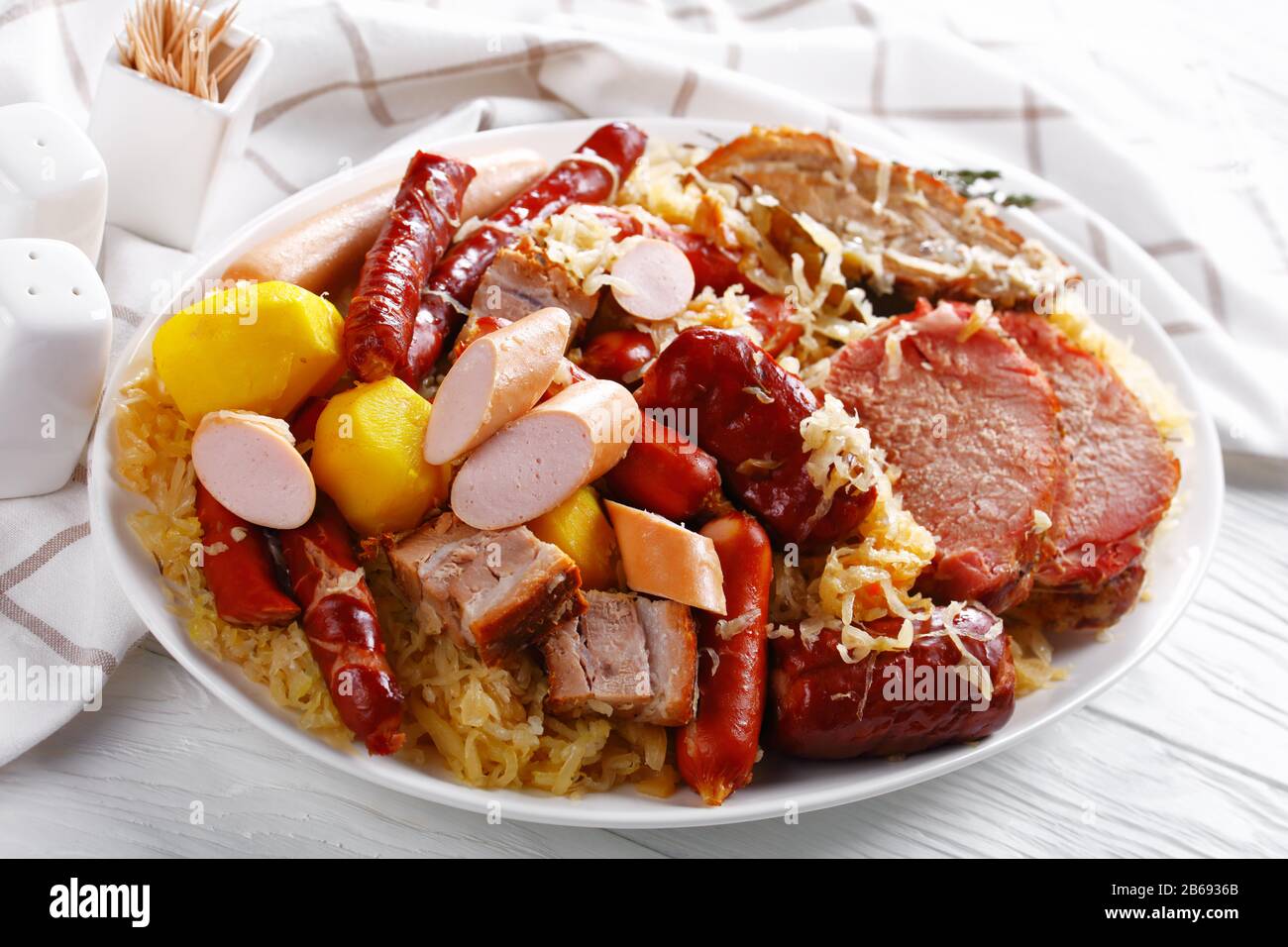 Crauti alsaziani francesi di spezzatino di cavolo acido grattugiato con carne di maiale, salsicce affumicate e pancetta cotta con patate yukon dorate brasate in whi secchi Foto Stock