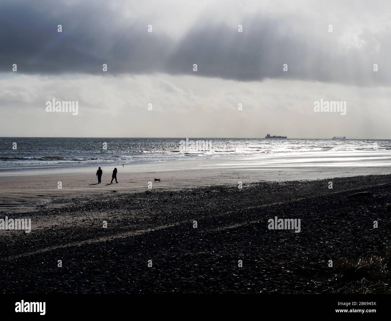 La gente si staglia contro un cielo invernale a piedi sulla spiaggia di Leven a Fife Scozia Foto Stock