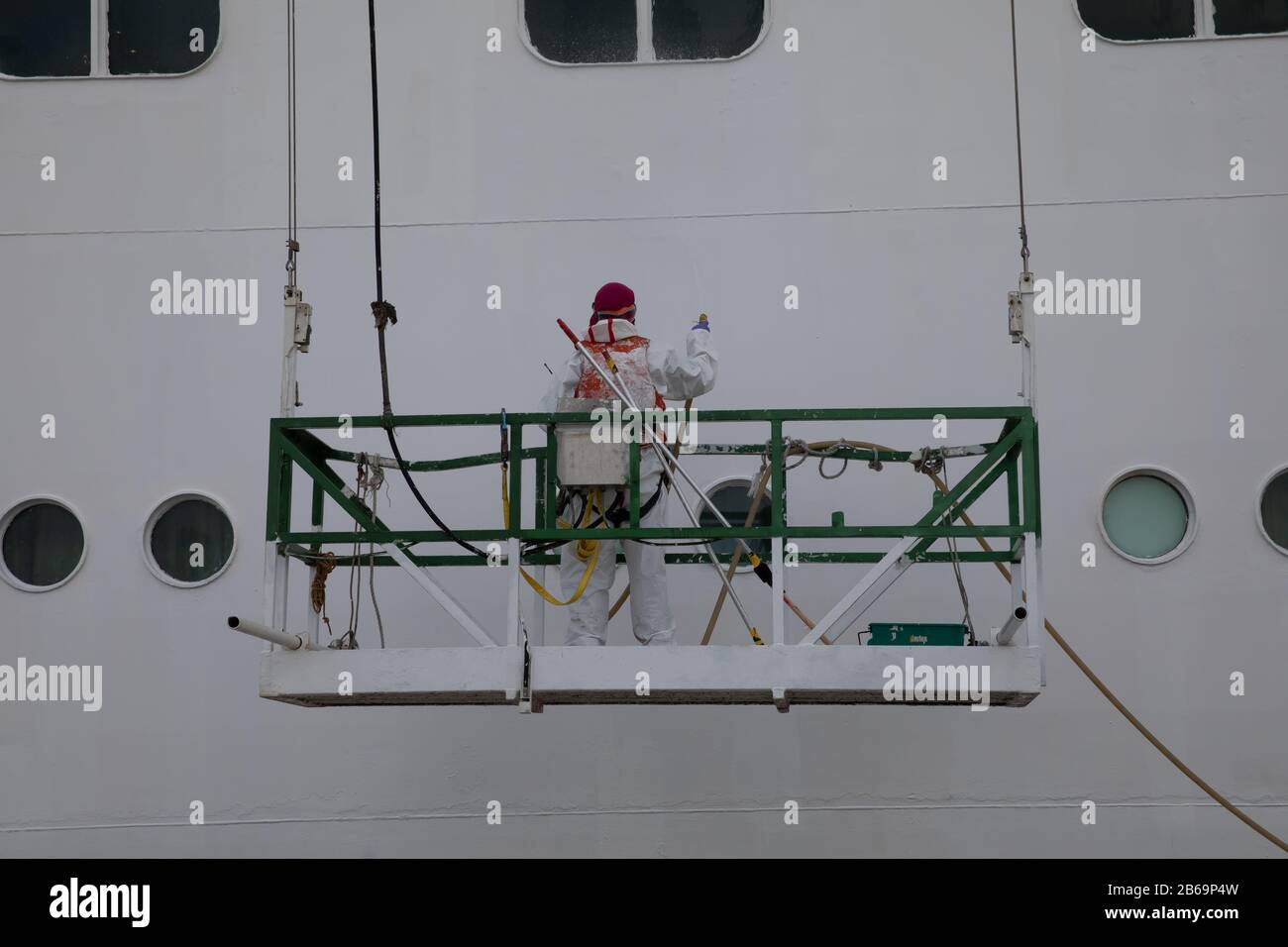 Un uomo che dipinge l'esterno di una nave da crociera a Las Palmas, Gran Canaria, una delle isole Canarie di Spains fuori dell'Africa nordoccidentale Foto Stock