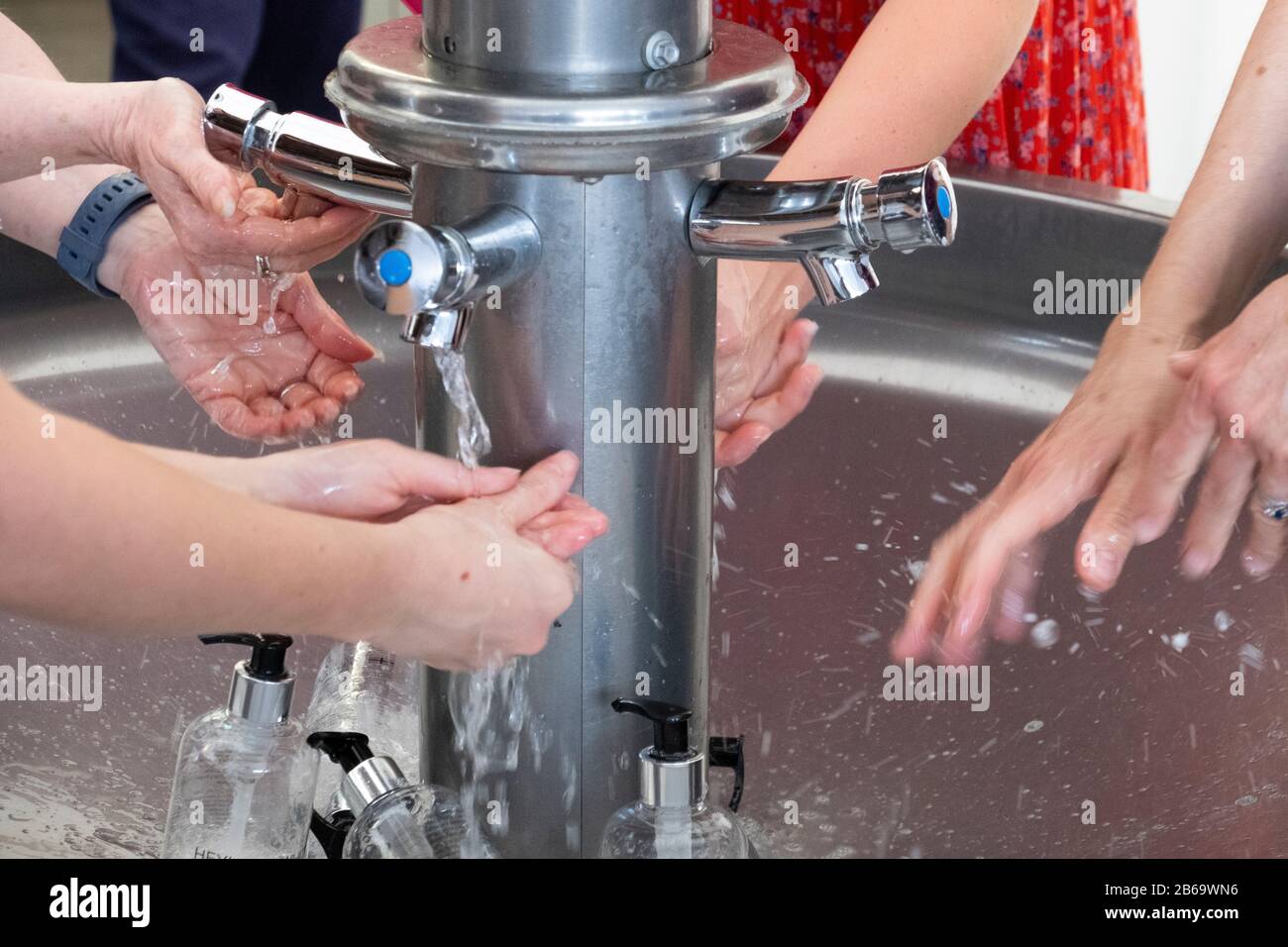 4 persone lavaggio a mano in un lavatoio comune Foto Stock