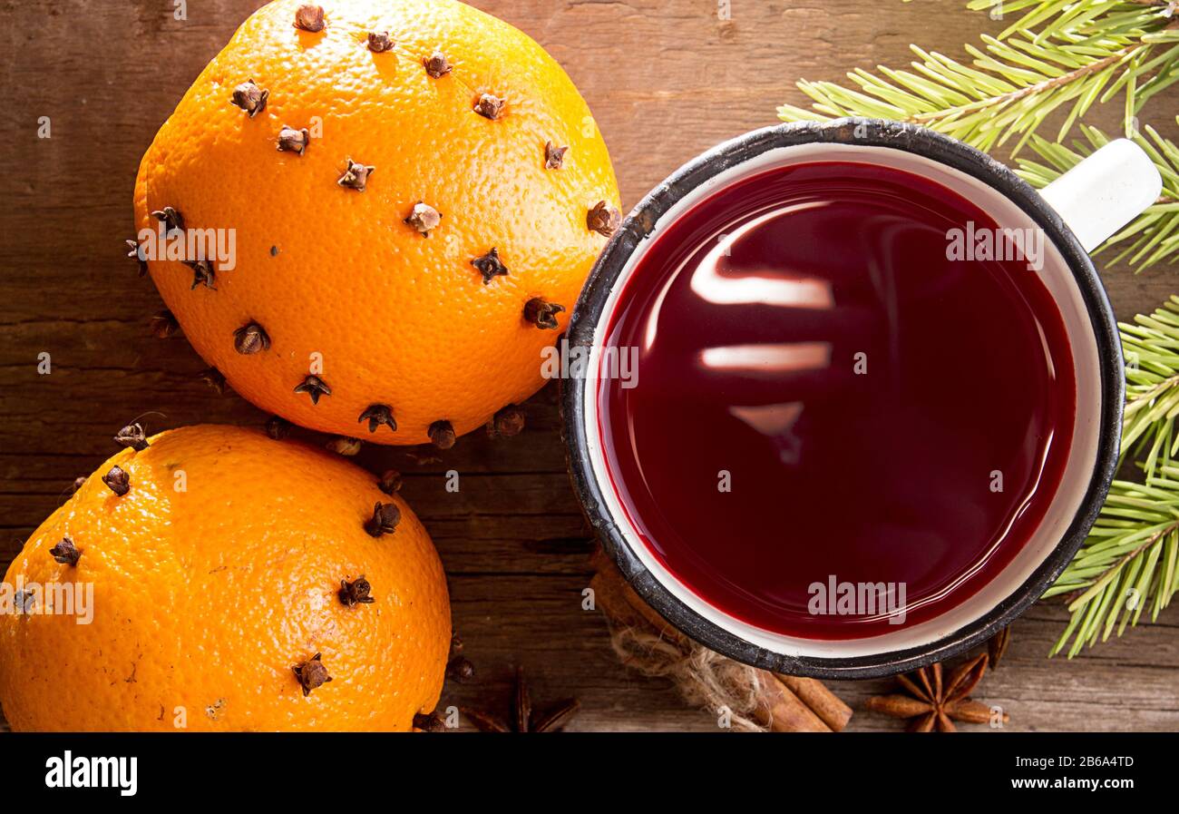 VIN brulé e due frutti arancioni decorati con garofano su vecchio sfondo di legno. Concetto Di Anno Nuovo Di Natale Foto Stock