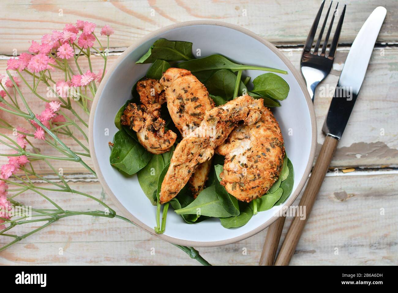 Filetti di pollo in una ciotola bianca con spinaci Foto Stock