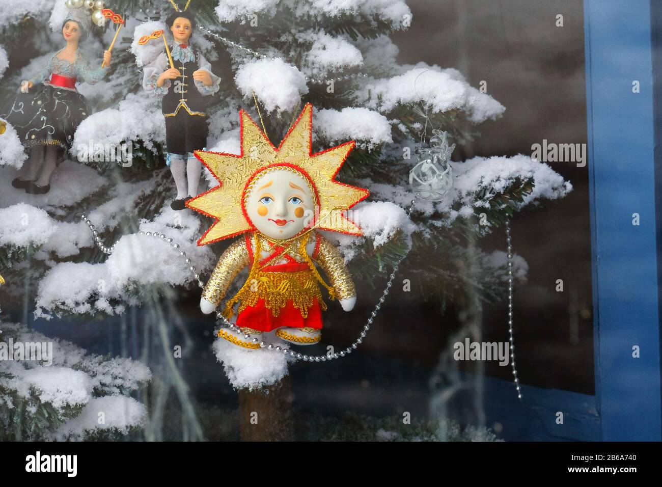 Giocattolo di albero di Natale in una finestra di negozio. Il sole con un volto. Vista dalla strada. Finestre sporche. Preparazione per il nuovo anno. Foto Stock